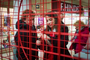 Woman attaches padlock to giant Valentine heart installation at Love Lock-In retail event, Cardiff