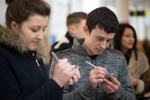 Couple writing Valentine messages on padlocks at Love Lock-In retail event, Cardiff