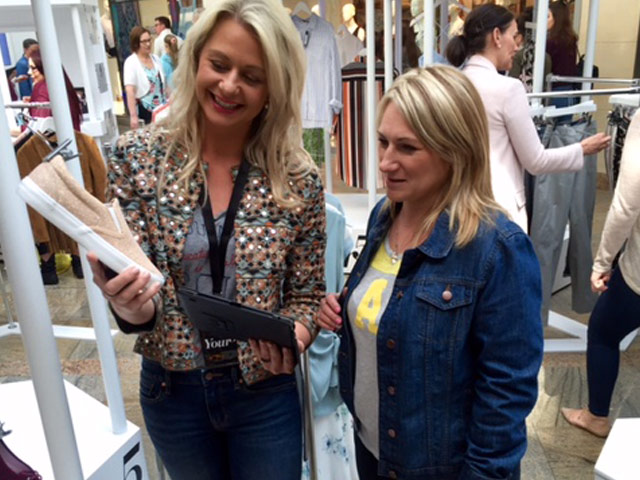 Two women, one customer and one brand associate, discuss shoes at a pop up shopping event on the mall