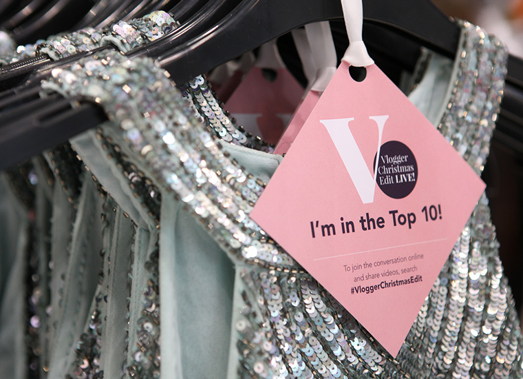 Close up detail of clothing tag on sparkly dress. The tag advertises a Vlogger event in the shopping centre