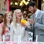 The experience economy - 2 women interact with the presenter of a live fashion event taking place in a shopping mall.