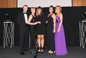 Smartly dressed group of men and women are posing on stage for aphotography after collecting a Northern Marketing Award