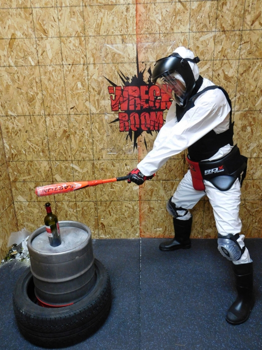 Retail-tainment - A man, wearing protective clothing, enjoys smashing objects with a baseball bat in the 'Wreck Room' experience at the outlets, Lake Elsinore in California, USA.